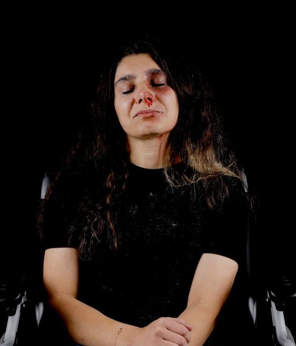 Woman peacefully meditating with a calm expression in a serene setting.